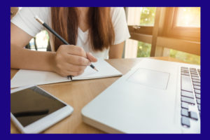 Female student taking notes from a book at library. Young asian woman sitting at table doing assignments in college library. Vintage effect style pictures.